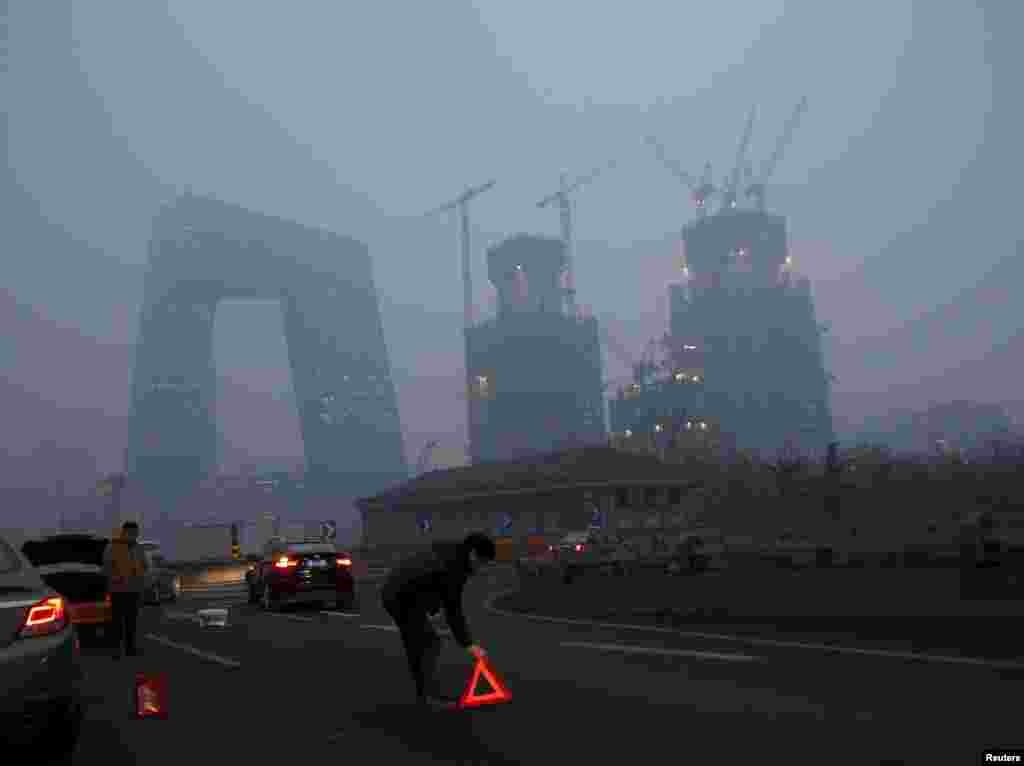 2015年12月8日,在北京首次发布空气污染红色警报后, 在雾霾中有车辆出事,有人放置橙色标志