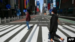 戴着口罩的行人走过纽约市时报广场。(2020年3月22日)