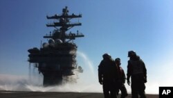 停泊在日本海岸外的美国罗纳德·里根号航空母舰的士兵在甲板喷水清理放射性污染 (资料照片)