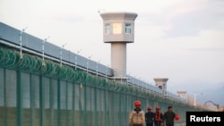 资料图片:几名工人在新疆一再教育营外走过。