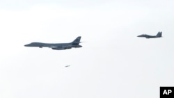 韩国国防部提供的图片显示,一架美国空军B-1B“枪骑兵”战略轰炸机(左一)往朝鲜半岛投下一颗炸弹。(2017年7月8日)