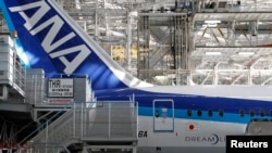 2013年4月28日,在全日空航空公司(ANA)的波音787梦幻客机下面,人们从事维修工作。