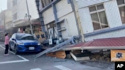 一名女子站在台湾花莲被地震震得歪斜的建筑旁。(2024年4月3日)