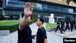 资料照:在北京的中国银监会入口处,保安人员巡逻,一位警察对摄影者摆出姿势,示意不让拍照。(2018年8月6日)