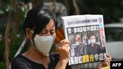 《苹果日报》两名高管——壹传媒行政总裁张剑虹与《苹果日报》总编辑罗伟光——的支持者在香港法庭外的抗议活动中手举《苹果日报》。(2021年6月19日)