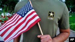 被美军解除兵役的22岁巴基斯坦籍新兵手举美国国旗接受采访。(2018年7月3日)
