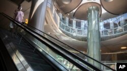 2022年5月21日,一名戴着口罩的女子在北京一家空空荡荡的商场里的自动扶梯上。