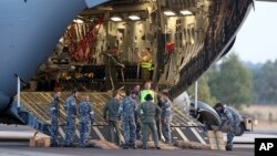 澳大利亚地勤人员准备从澳大利亚皇家空军C-17运输机上卸下搜索海面所需要的海鹰直升机, 2014年3月28日