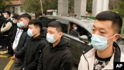 资料照片:世界卫生组织的专家达扎克在湖北省武汉市进行了实地考察后,乘坐汽车离开湖北疾病预防控制中心的一排安全人员。(2021年2月1日)