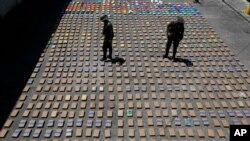 FILE - Police officers walk among packages of seized cocaine at the pacific port of Buenaventura, Colombia, Aug. 10, 2017.