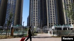 资料照:2023年9月27日,中国北京,一名男子拉着手推车经过恒大住宅区的住宅楼。(路透社)
