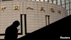 资料照:一名男子坐在中国人民银行总部大楼外。