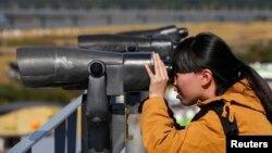 一位中国游客在韩国境内分隔韩朝的非军事区附近的临津阁用望远镜向北观望。(2013年10月16号)
