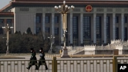 戴着口罩的中国武警士兵在北京人大会堂前空旷的天安门广场上行走。(2020年2月23日)