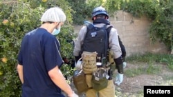 联合国化武专家(右)8月26日在大马士革郊区一个据称遭受化武袭击的现场搜集证据