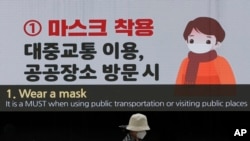 在韩国首尔东大门设计广场,一名戴着口罩的妇女经过显示预防冠状病毒的屏幕。(2020年4月19日)