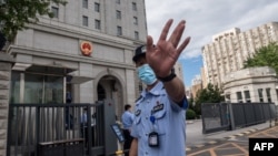 当押送任志强的警车抵达北京第二中级人民法院时一名警察在向记者做手式。(2020年9月11日)