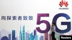 一名男子走过在北京举办的中国国际信息通信展览会的一块华为公司5G技术广告牌。(2018年9月26日)
