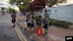 中国驻港部队军人星期六(11月16日)在香港清除抗议活动之后留下的路障和垃圾。