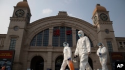 资料照:2020年4月7日,在中国湖北省武汉市恢复出境交通前夕,身穿防护服的人员走过汉口火车站。