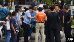 在北京的中国银监会附近,警察对中国网络理财民间集资受害者讲话,旁边是保安人员(2018年8月6日)。受害者从中国各地到北京请愿维权。