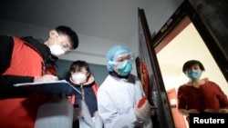 资料照片:中国天津的社区工作人员和医疗人员挨门挨户地检查居民健康状况。(2020年2月12日)