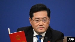资料照:中国前外交部长秦刚在一个记者会上手拿一本中国宪法。(2023年3月7日)