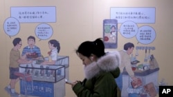 2019年1月3日在北京一个地铁站,女子看着手机,走过推广iPhone的壁画。