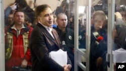 Former Georgian President Mikheil Saakashvili stands behind the glass and talks to reporters before the hearing in a court room in Kyiv, Ukraine, Dec. 11, 2017.
