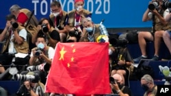 资料照片:在2020东京夏季奥运会一次游泳决赛期间,人们在看台上亮出一面中国旗帜。(2021年7月29日)