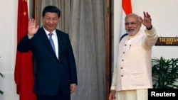 India's Prime Minister Narendra Modi (R) and China's President Xi Jinping wave to the media during a photo opportunity ahead of their meeting at Hyderabad House in New Delhi, Sept. 18, 2014.