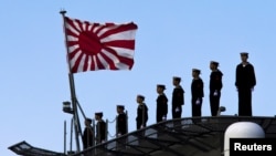 2015年3月25日,日本海军站在即将起航的出云级护卫舰甲板上,这艘军舰即将驶离东京南部的横滨日本联合海上造船厂。