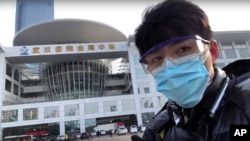 中国公民记者陈秋实在中国中部湖北省武汉市一场病毒性疫情中,在一家会议中心改建的临时医院前面。(2020年2月4日)