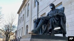 美国哈佛大学校园里的约翰·哈佛塑像,疫情之下有人为他戴上了口罩。(2020年3月14日)