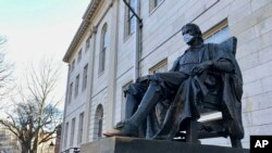哈佛大学一座地标雕塑,疫情之下有人为它也戴上了口罩。(2020年3月14日)