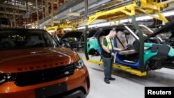 FILE - Worker George Baker looks at a build card for a vehicle destined for China at the Jaguar Land Rover facility in Solihull, England, Jan. 30, 2017. 英国捷豹路虎制造厂的一名工人正在看一张装配卡。(资料照片)