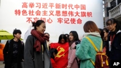 资料照:上海大学生在一幅宣传习近平的大标语前照相后将一面中共党旗收起来。(2017年11月19日)